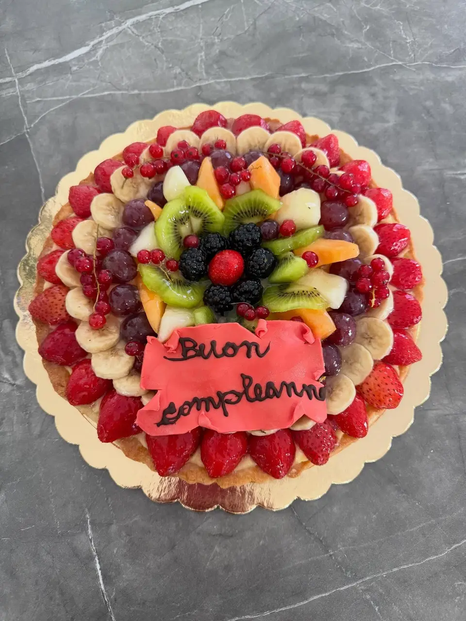 Crostata di frutta fresca vista dall’alto, decorata con la scritta Buon compleanno