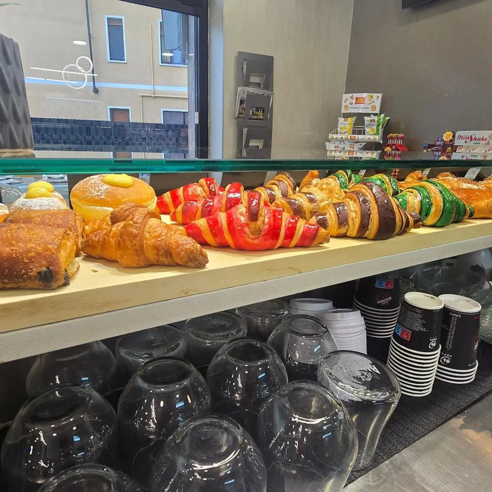 La vetrina del bar con cornetti e brioche, anche bicolori rossi e verdi, e krapfen