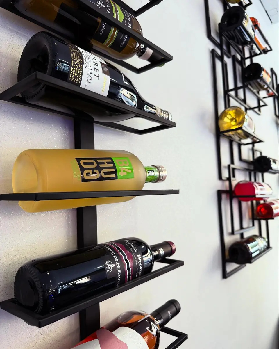 Bottiglie di vino sulle rastrelliere in ferro nero della sala